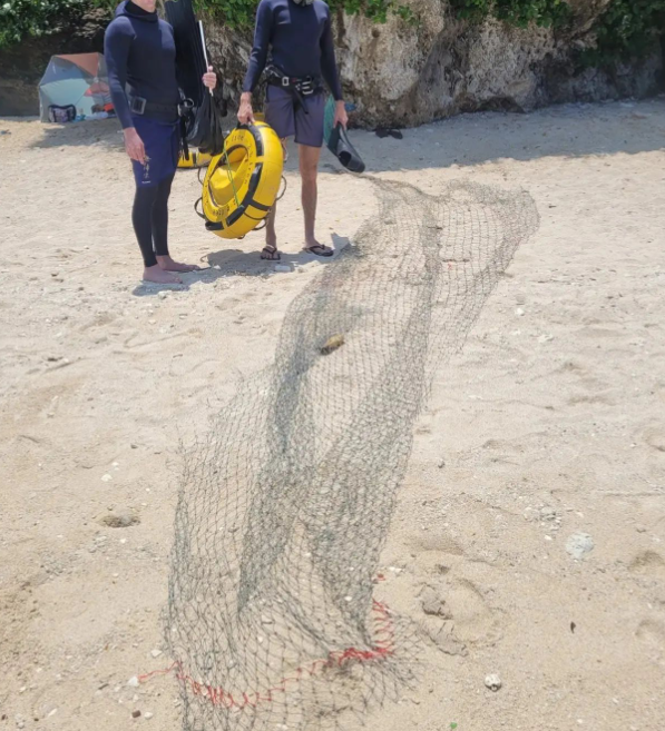 Divers cleaning up fishing nets after a dive.